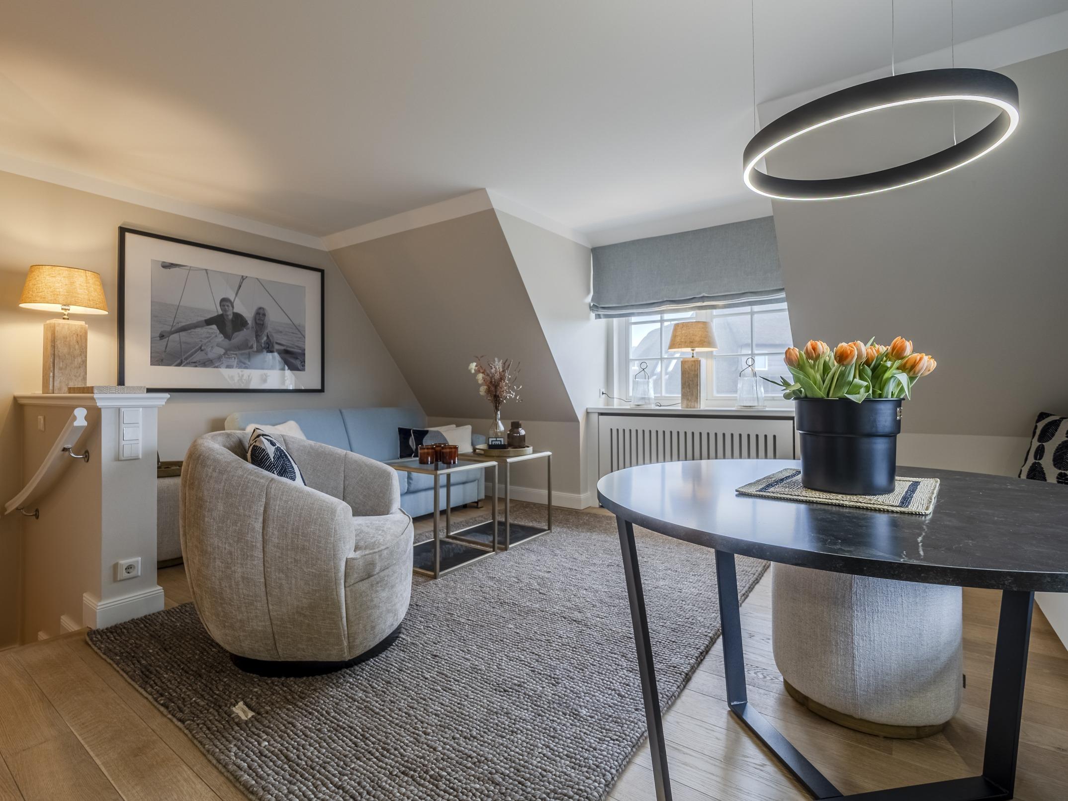 Stilvoller Wohnbereich mit Sofa, Sessel und Wandbild in der lichtdurchfluteten Ferienwohnung Rantum.